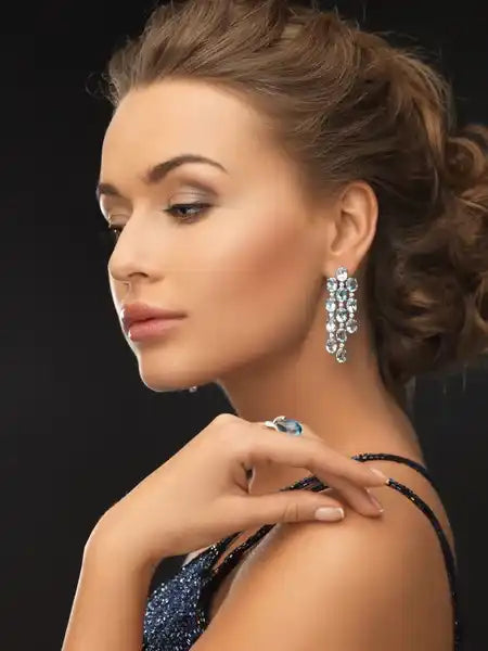 Profile view of a woman wearing sparkling earrings and a dark sequined dress.